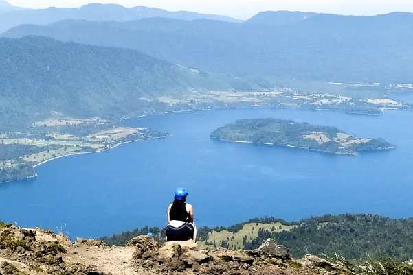 Persona sentada en la cumbre del Cerro Sarnoso viendo el paisaje y el lago Puyehue