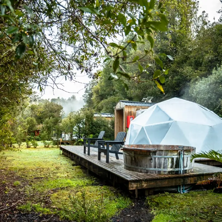 Domo de termas Aguas Calientes con terraza de madera y tinaja, rodeado de bosque