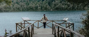 Persona en mirador de madera con vista a la laguna Espejo y el bosque en Aguas Calientes.