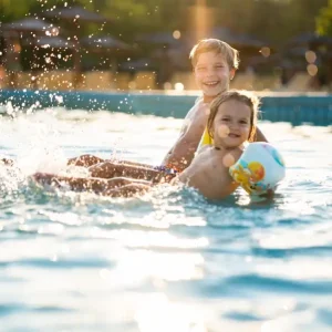 Dos niños jugando en la piscina abierta de Termas Aguas Calientes por la tarde