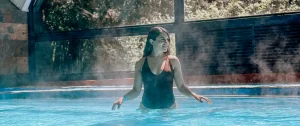 Mujer en traje de baño negro en piscina techada con vapor en Termas de Aguas Calientes